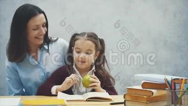 勤奋的女儿读书.. 妈妈带了一个绿<strong>苹果</strong>。 坐在<strong>灰色</strong>背景上。